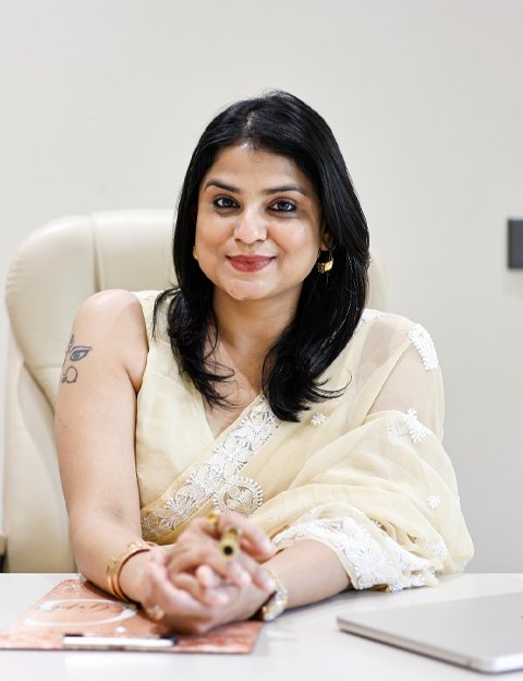 Dr. Anchal Gupta at her desk in a cream saree