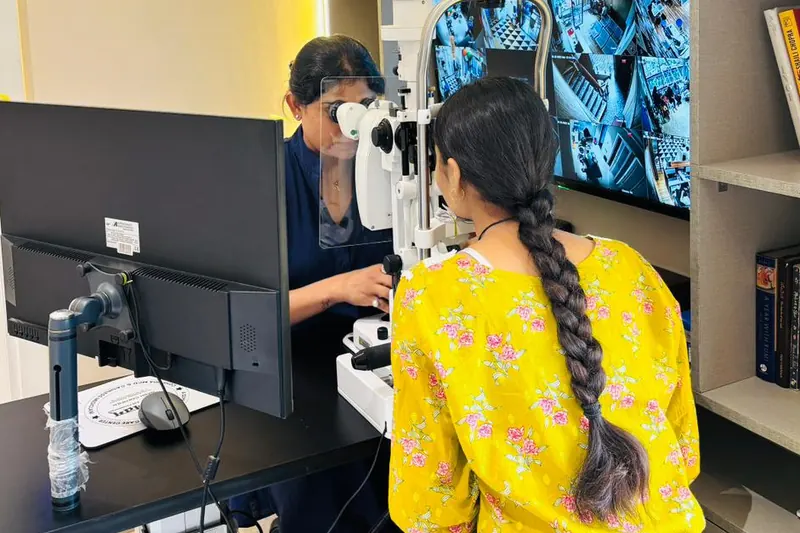 Dr. Anchal Gupta examining a young patient at the slit lamp, the scans on the screens beside them