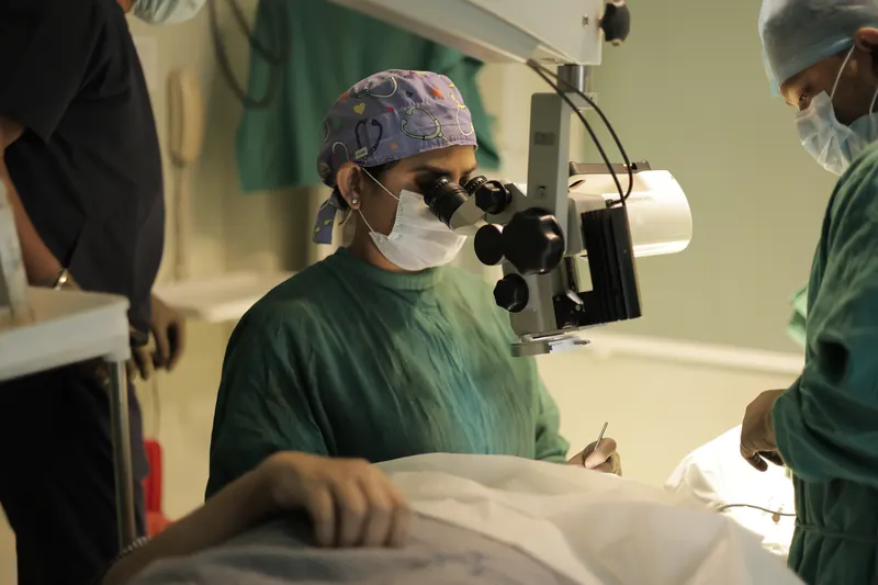 Dr. Anchal Gupta operating at the surgical microscope