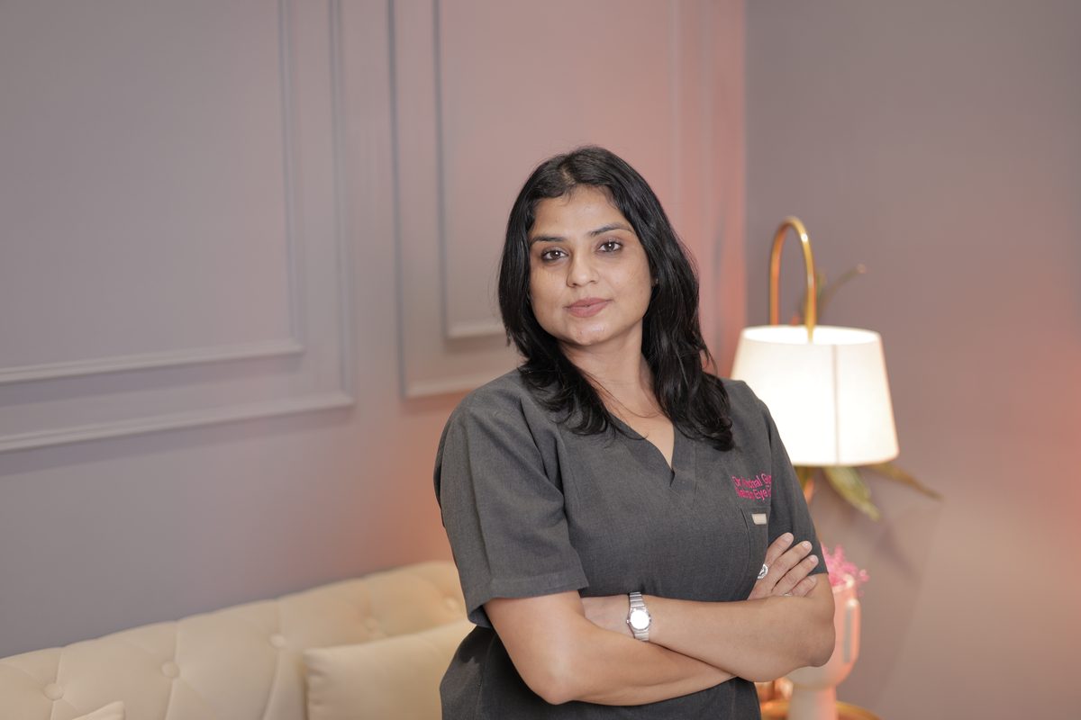 Dr. Anchal Gupta in black scrubs, arms crossed, beside a lamp