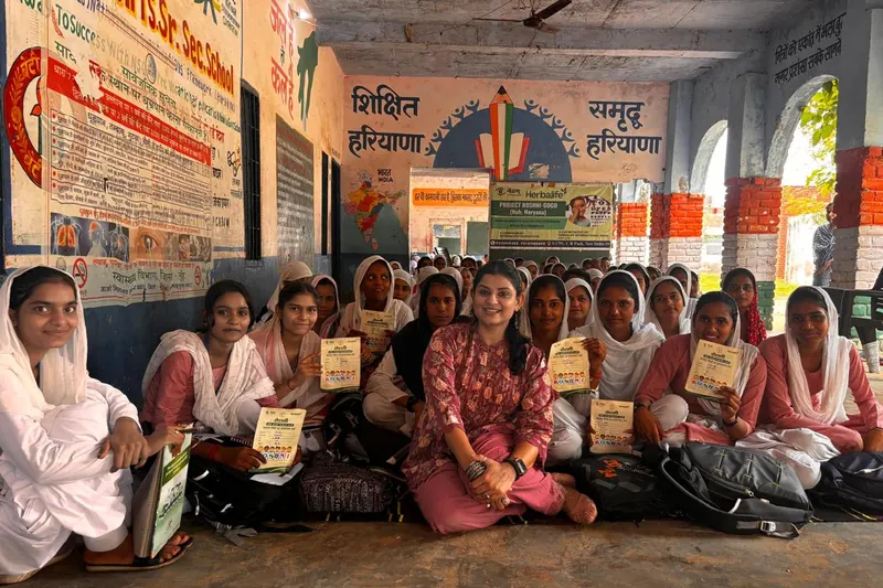 Dr. Anchal Gupta seated among schoolgirls holding their Roshini screening cards at a school camp
