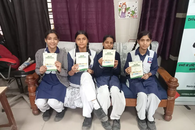 Schoolgirls holding their Roshni screening cards